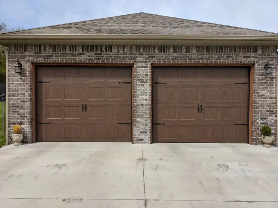 Two brown carriage doors in a brick double garage, installed by Integrity Overhead Door