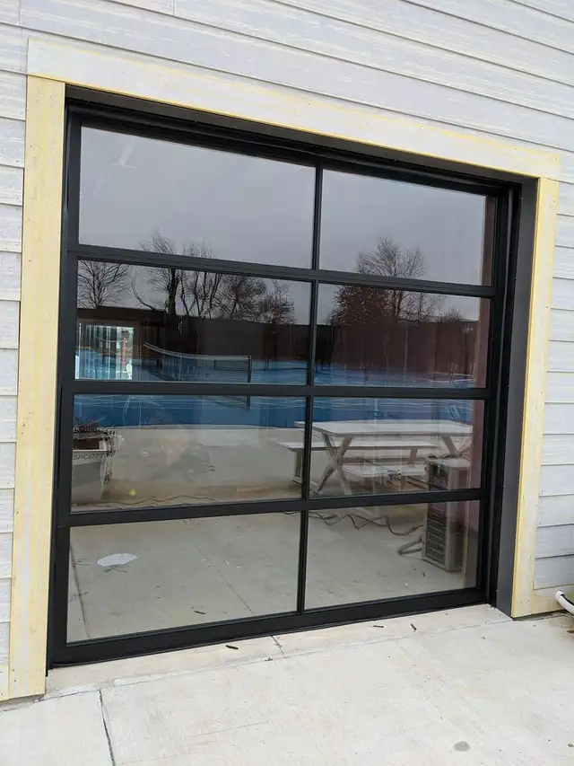 Black-framed full-view glass door on a pool house, installed by Integrity Overhead Door