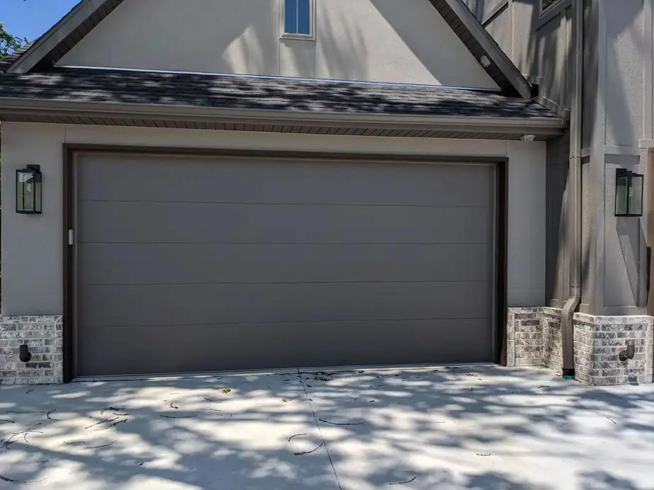 Flush modern grey door on a stucco and stone home, installed by Integrity Overhead Door