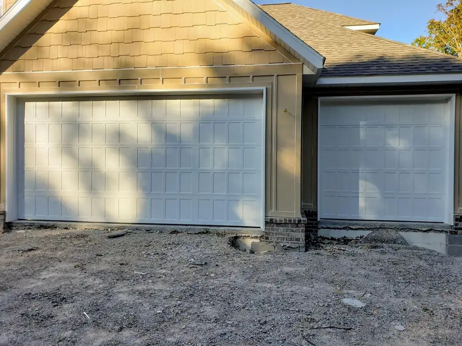 Two white raised-panel garage doors on a new build, installed by Integrity Overhead Door
