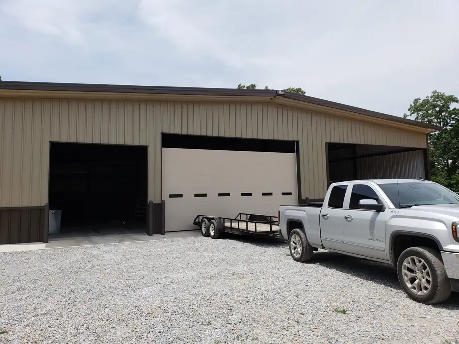 Tan shop with one closed bay and two open bays, installed by Integrity Overhead Door