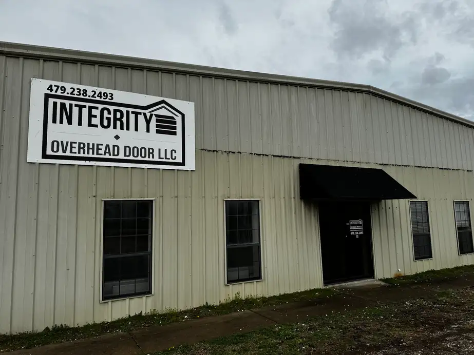 The Integrity Overhead Door LLC steel building on June Self Drive in Springdale with the company sign and phone number